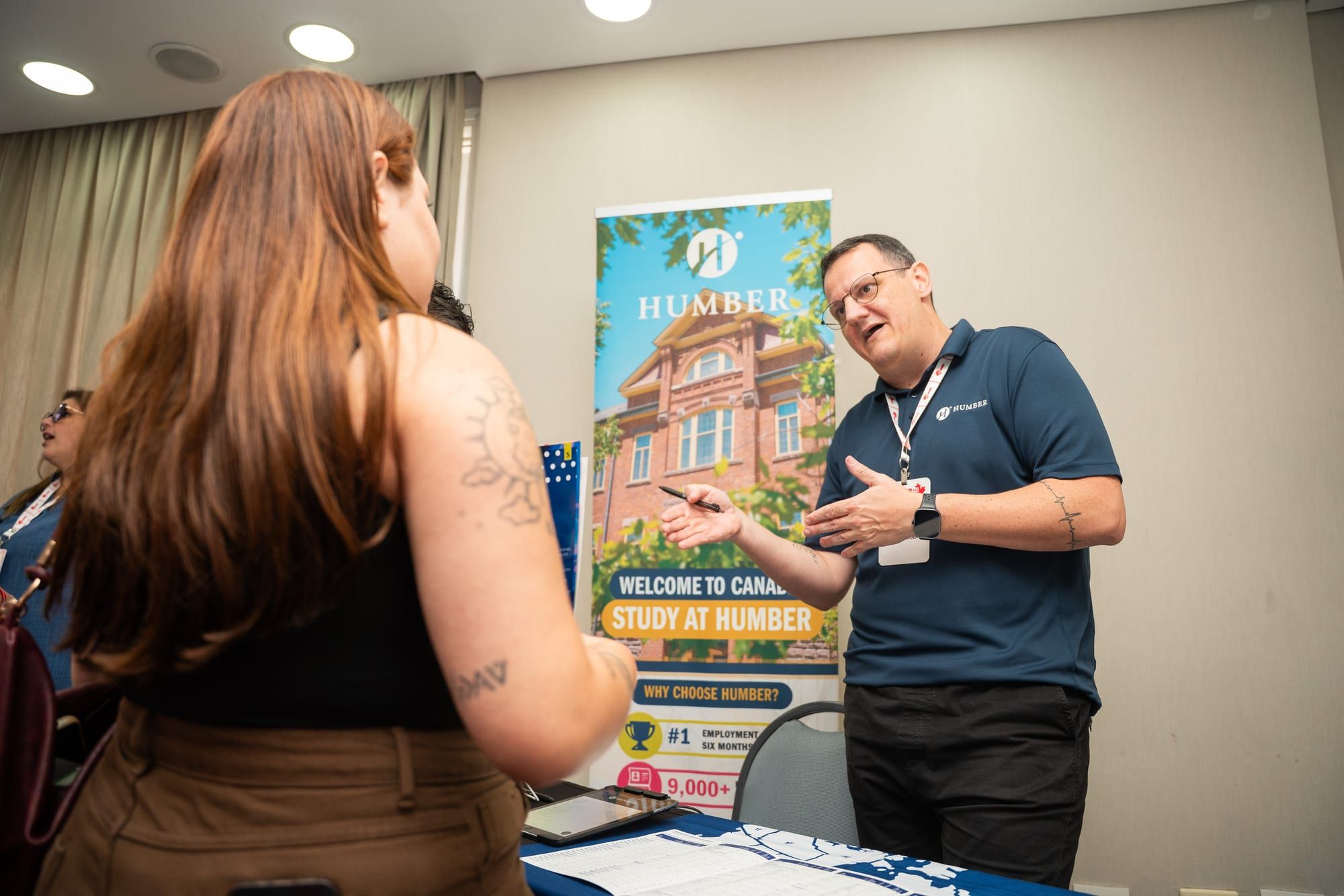 Representante da instituição conversando com visitante no estande