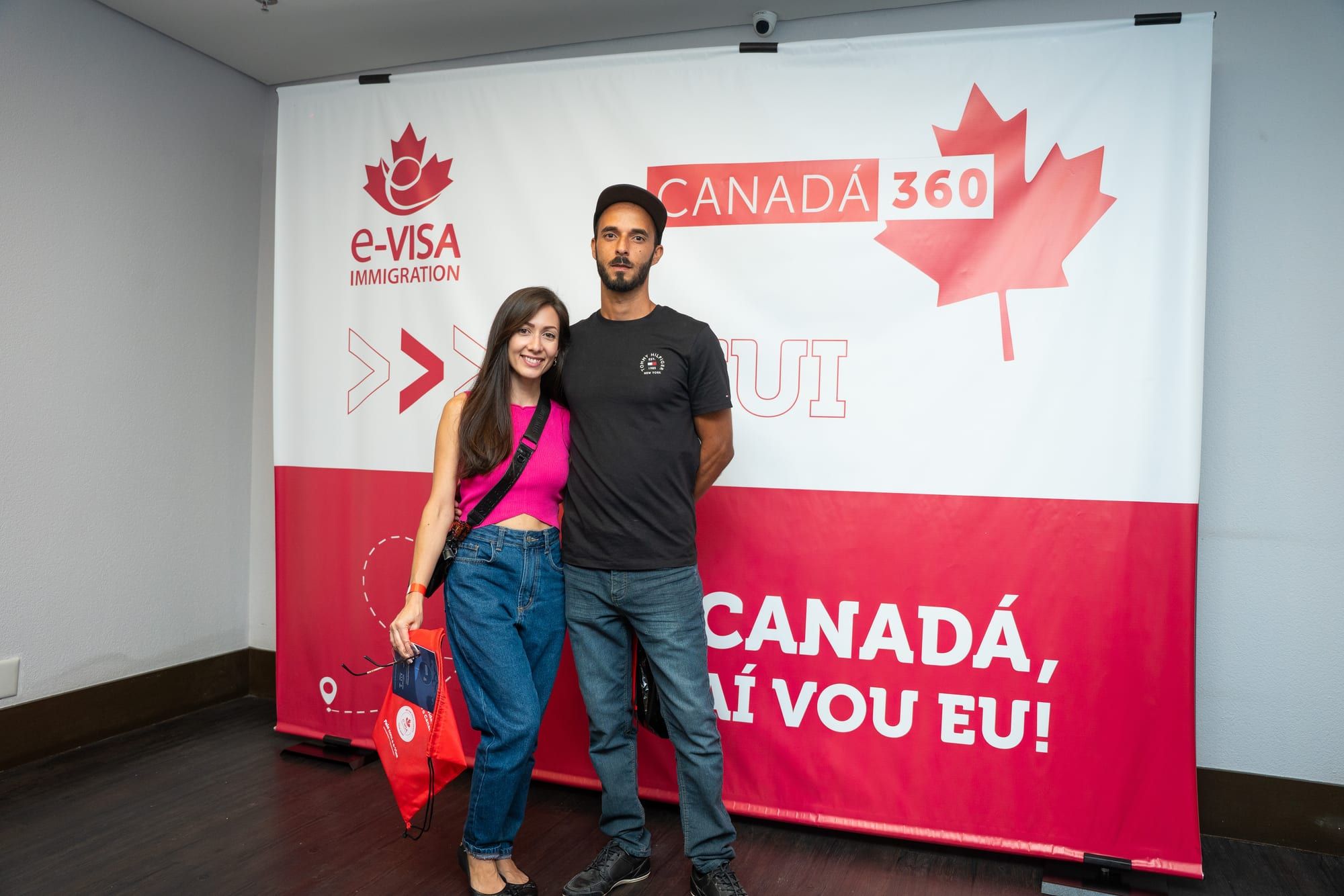 Casal posando diante do painel do evento