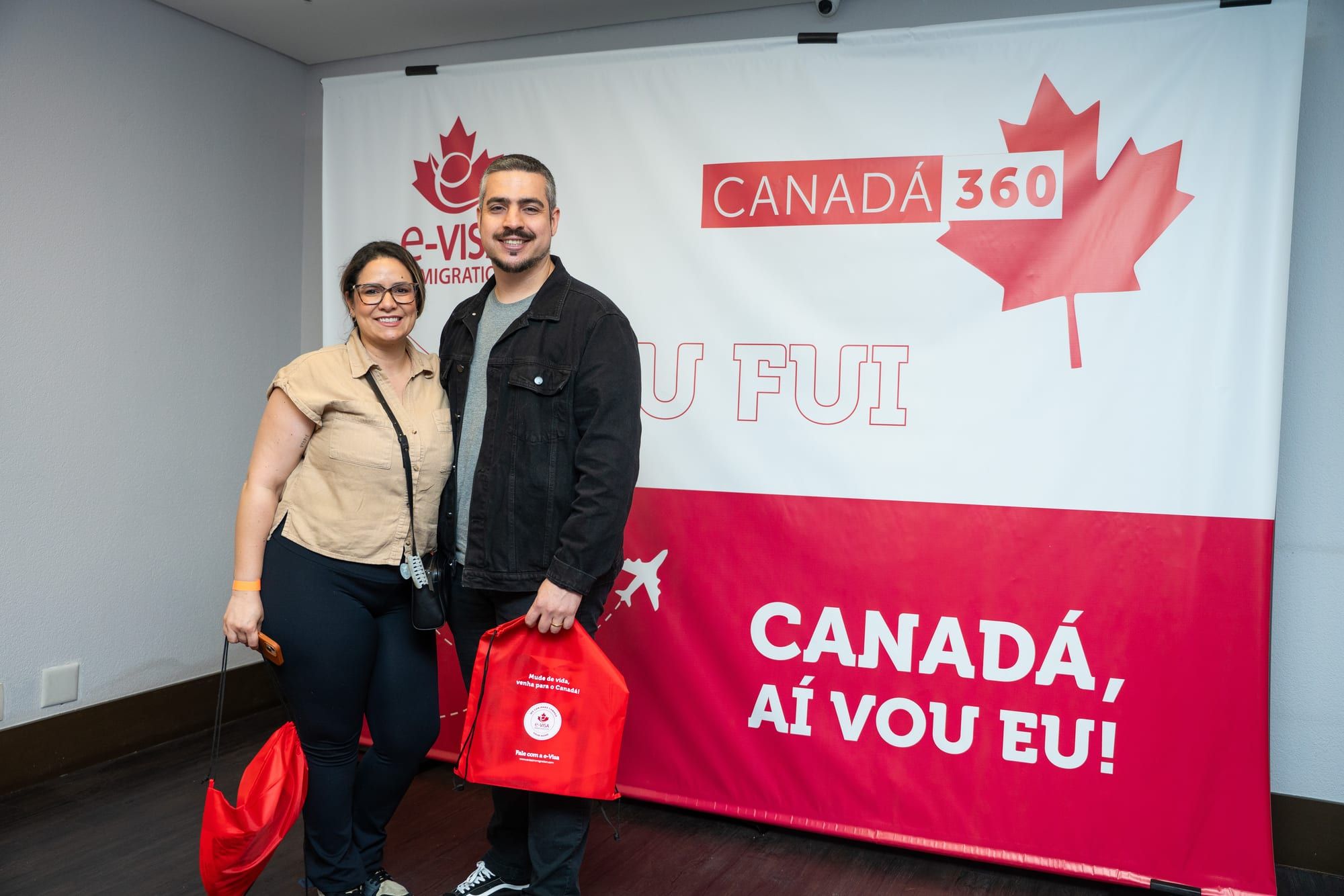 Participantes com a mochila do kit diante do painel